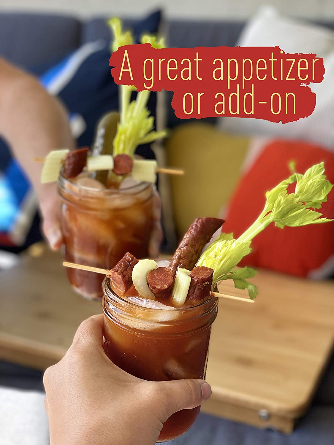 Hands toasting and clicking mason pickle jars of Bloody Mary's with celery and Aurelia's Spanish Chorizo Snack Sticks as a garnish.