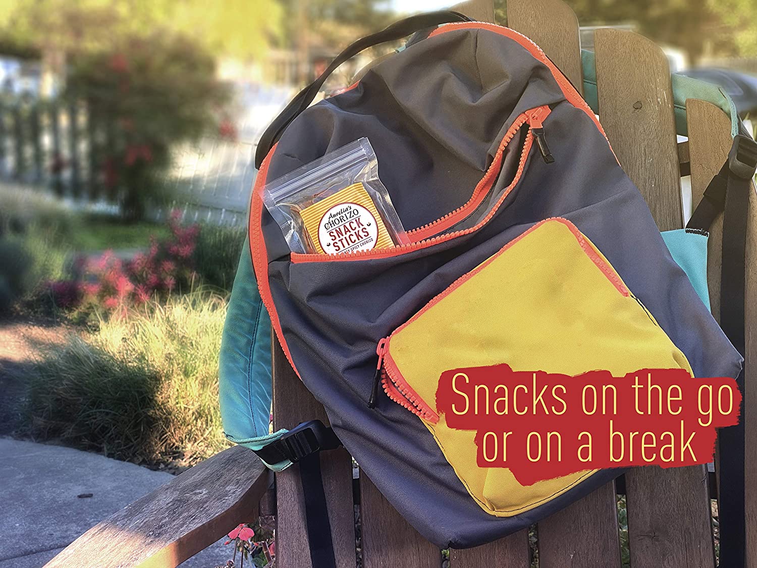 Blue and yellow backpack slung over an Adirondack chair with a package of Aurelia's Spanish Chorizo Snack Sticks peeking out from one of the pockets.