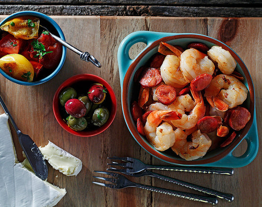 Large ceramic bowl filled to the brim with garlic shrimp and slices of Spanish chorizo.