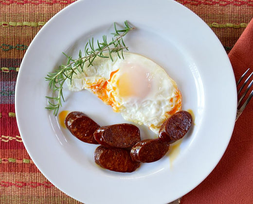 Sunny side up egg with crispy, spicy Spanish chorizo slices on a breakfast plate.