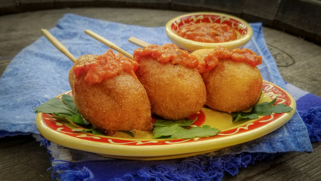 Mini Spanish Corn Dogs topped with Romesco Sauce on a small tapas plate.