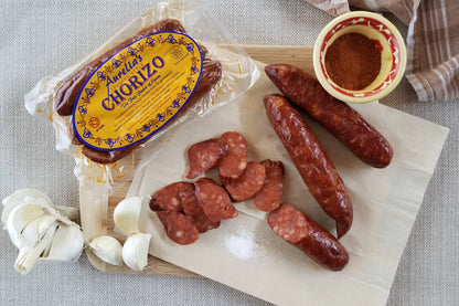 Package of Aurelia's Spanish Chorizo on a cutting board with a couple of links and slices of chorizo, garlic, sea salt and paprika.